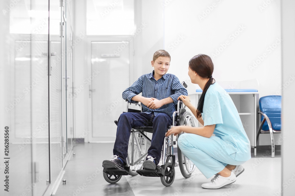 Young female doctor taking care of little boy in wheelchair indoors Young female doctor taking care of little boy in wheelchair indoors