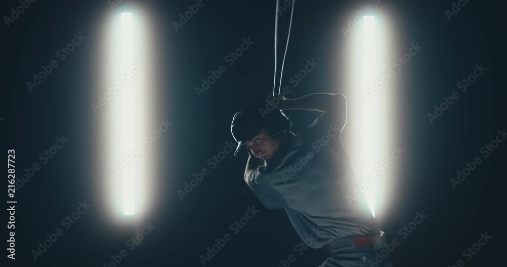 Caucasian professional baseball player batter hitting a ball against dark background. 4K UHD 60 FPS SLOW MOTION