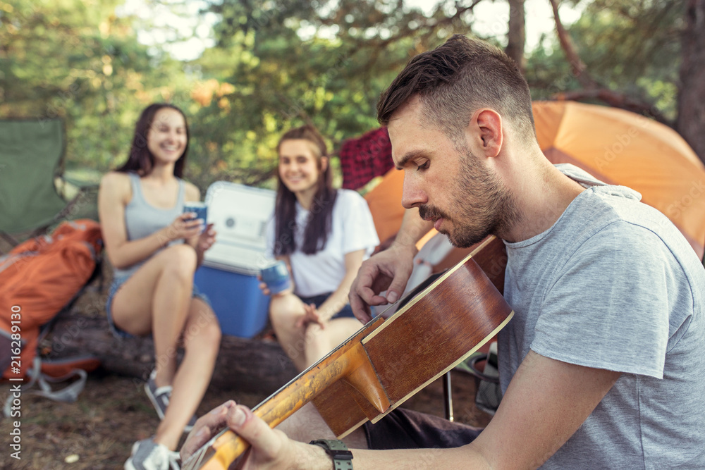 Party, camping of men and women group at forest. They relaxing, singing a song