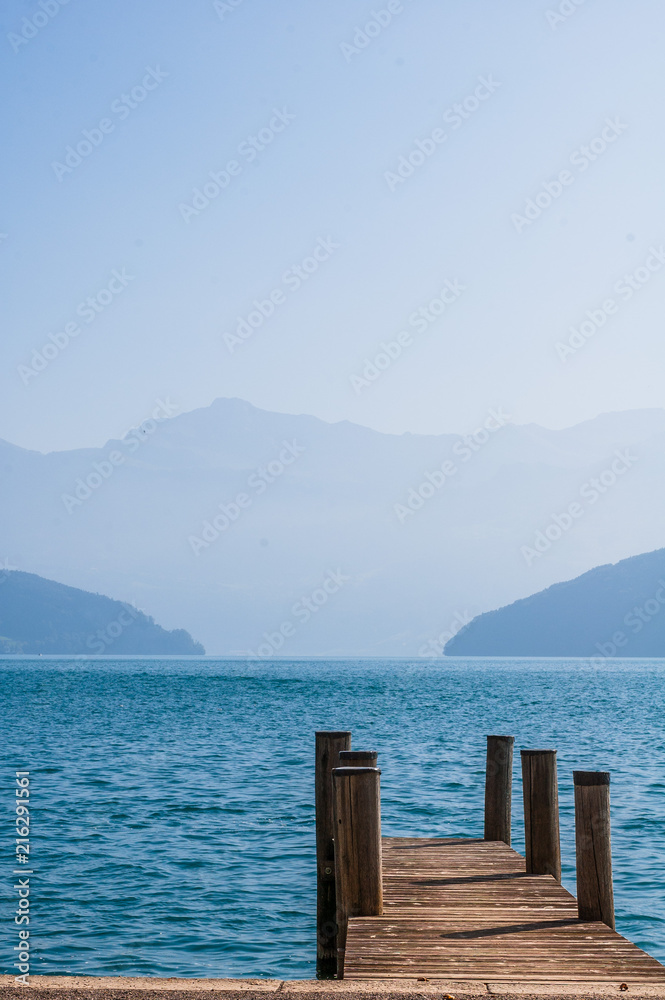 Panorama of mist mountains and Quatre Cantons lake with wood deck foreground, near Lucerne, Switzerland. Panorama of mist mountains and Quatre Cantons lake with wood deck foreground, near Lucerne, Switzerland.