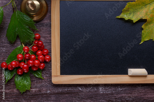 Back to school concept. Chalkboard and school bell on dark brown background. Top view, flat lay. Copy space.
