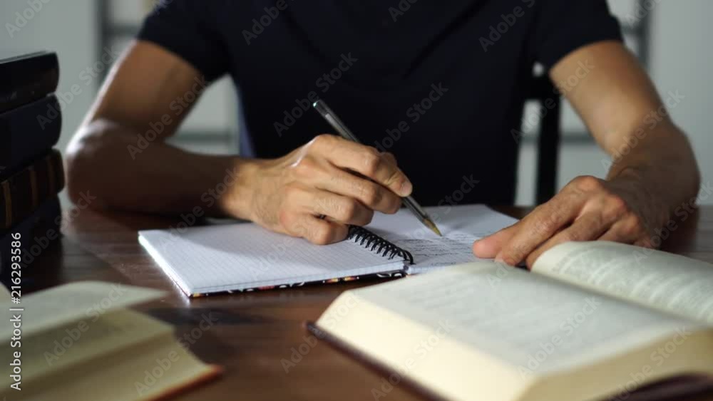Close-up student's hand writting in a notebook on the table. Studying, university, lessons education concept.