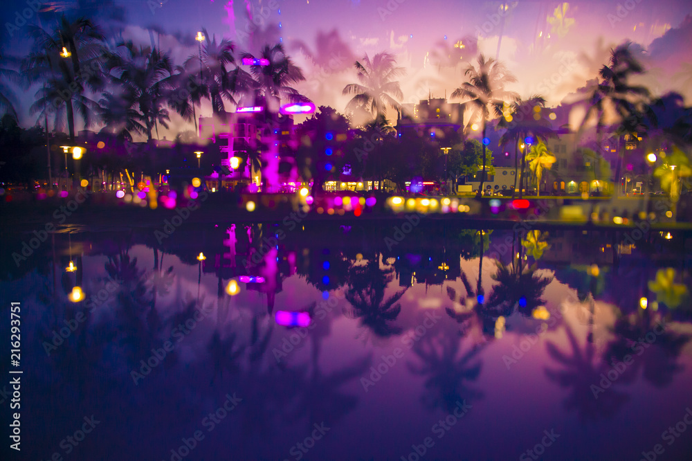 Naklejka premium Abstrakcyjny widok wielokrotnej ekspozycji o zmierzchu palm i neonów Ocean Drive odbijających się w kałuży o zmierzchu w South Beach, Miami, Floryda, USA