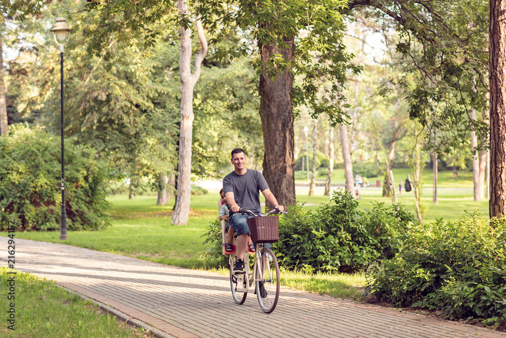 Family cycling outdoors – Father and son riding bike in the park.