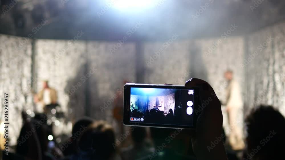 Concert phone silhouette shooting video in a fan crowd in spot light lumiere
