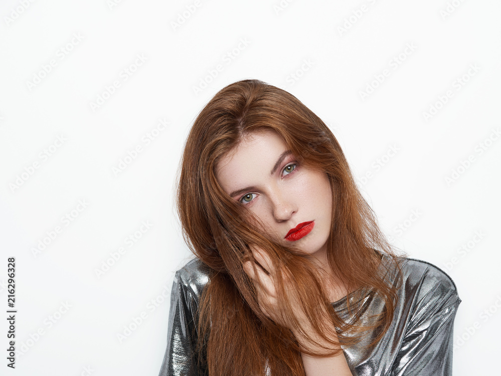 Headshot of young beautiful excited woman with gorgeous natural red hair, red lips, green eyes in glossy silver blouse on white background Headshot of young beautiful excited woman with gorgeous natural red hair, red lips, green eyes in glossy silver blouse on white background