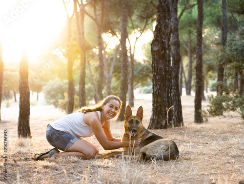 Young attractive latin woman teaching and loving her beautiful cute german shepherd dog in the park at sunset in nature care support happiness peaceful friendship training animals lifestyle concept.