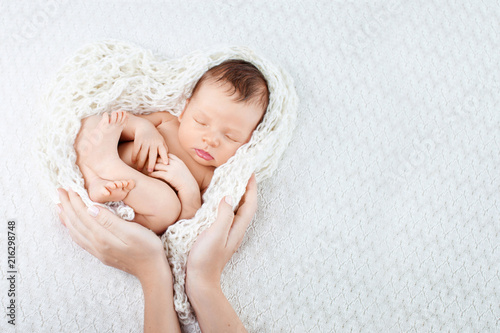 Sleeping newborn baby  in mother hands - hearth shape