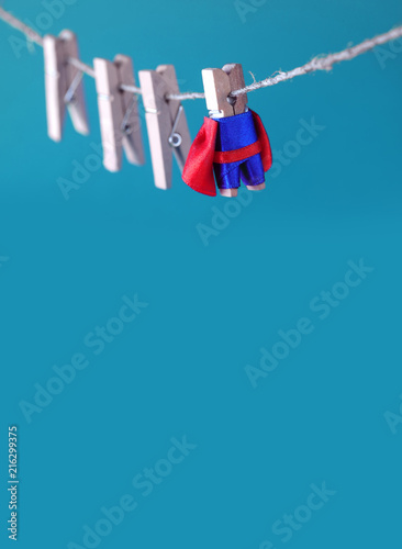 Powerful super hero superstar clothespin character in blue suit red cape. leadership and team working concept. blue background. copy space