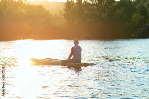 Sup surfer sits on the sup board in the golden light © sanechka