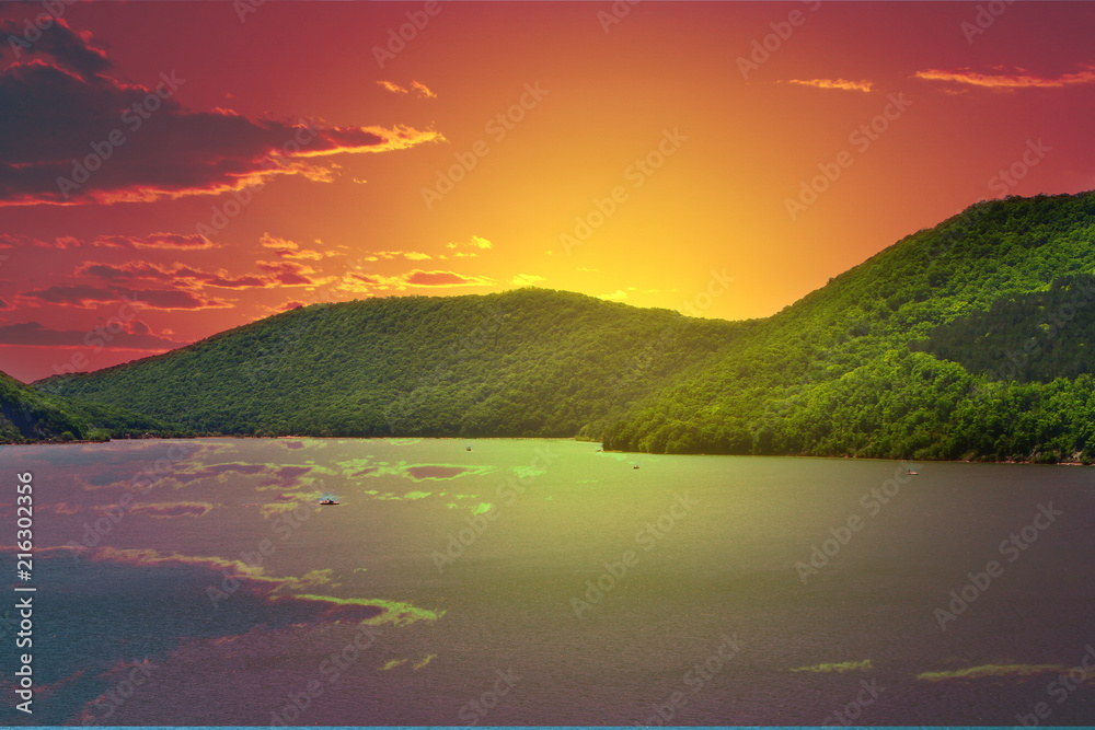 Mountains with green forest on a lake shore on the red sunset sky with clouds background