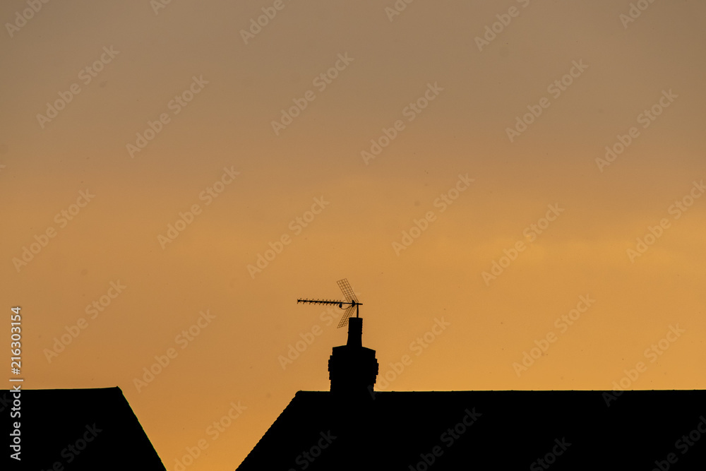 Summer sunset with silhouette of residential homes and tv aerial