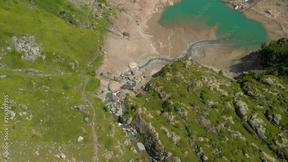 The drone is flying over a lake in the french Pyrenees (mountains). Camera is pointing down in the beginning showing the beautiful lake and dam, and as it tilts up, wonderful landscape is revealing. The drone is flying over a lake in the french Pyrenees (mountains). Camera is pointing down in the beginning showing the beautiful lake and dam, and as it tilts up, wonderful landscape is revealing.
