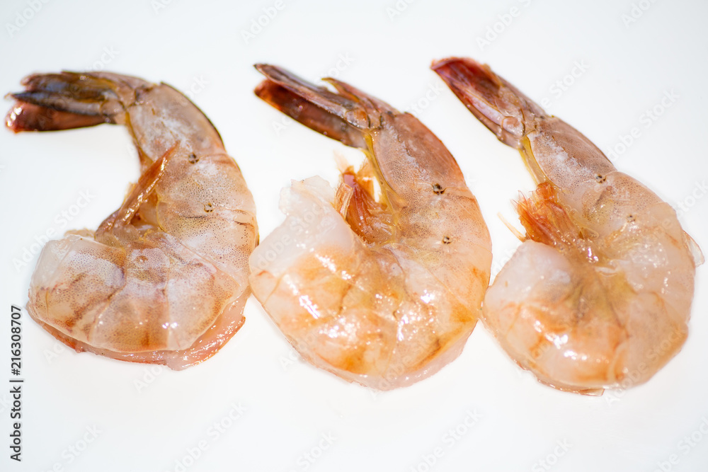 Three fresh and  washed shrimp just rinsed and prepped to be cooked.on the kitchen counter.