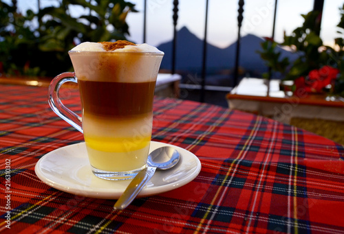 Traditional Canarian coffee Barraquito with separated layers of milk condensed and liquor on the terrace of cafe in Tenerife,Canary Islands,Spain.Selective focus. photo