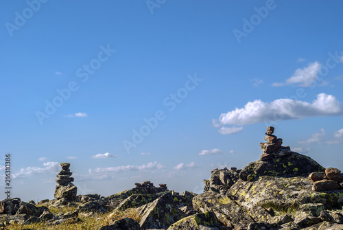 bright landscape of a high-altitude plateau with folded travelers pyramids cairns of stones under a blue sky with clouds.. photo