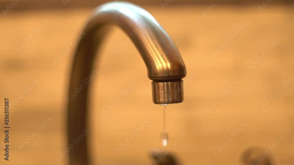 A dripping kitchen sink faucet with a shallow depth of field. A dripping kitchen sink faucet with a shallow depth of field.
