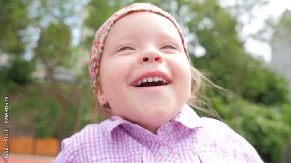 Happy little child girl swaying on swing playing park playground face portrait Happy little child girl swaying on swing playing park playground face portrait