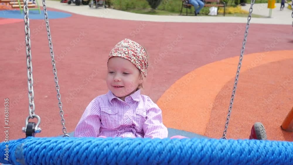 Happy little child girl swaying on swing playing on outdoors park playground Happy little child girl swaying on swing playing on outdoors park playground