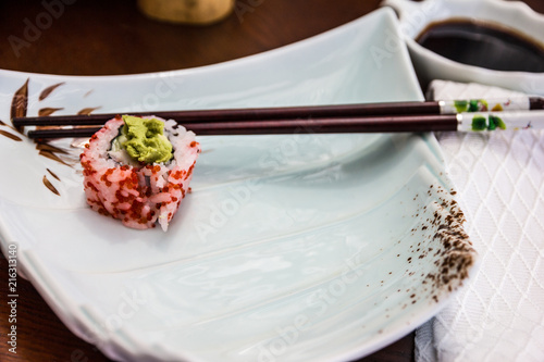 sushi roll and sticks on the white plate