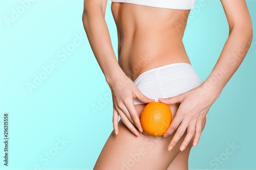 Female slender body in sport underwear holding fruit