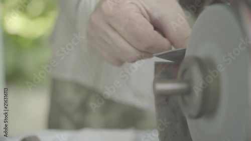 man sharpens a knife on a grindstone, close-up photo