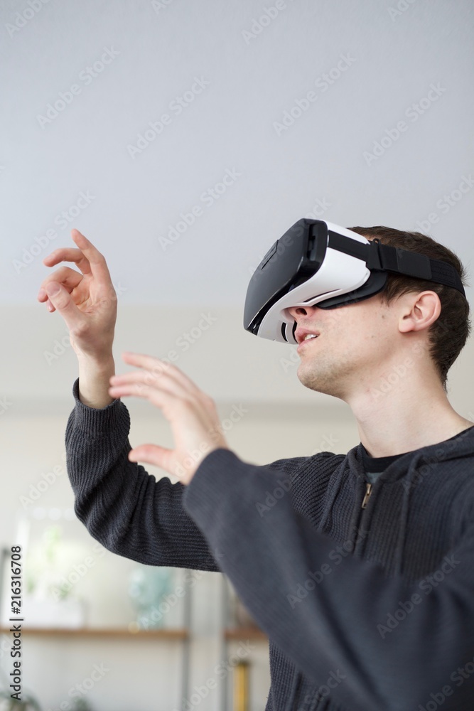 Man in VR goggles interacting in living room Man in VR goggles interacting in living room