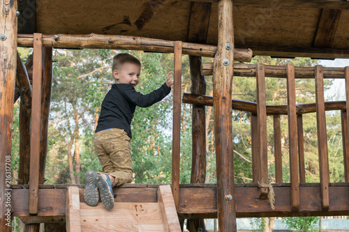 A little boy is climbing a children's hill in the park in the summer. The child is 3-5 years old. Active rest on a children's playground.