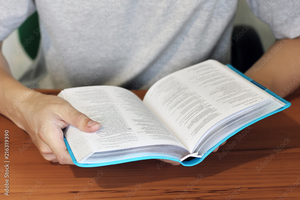 Fototapeta premium Open Bible. The guy is reading the Bible