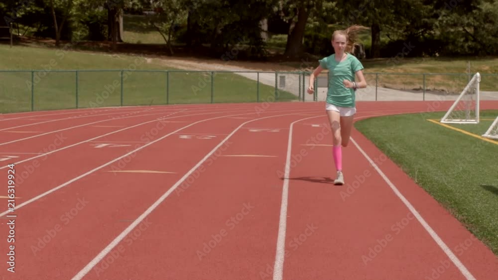 Teen girl athlete books it down the track and past the camera in slow motion Teen girl athlete books it down the track and past the camera in slow motion