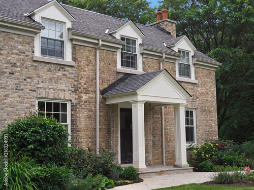 portico entrance of small brick house with dormer windows