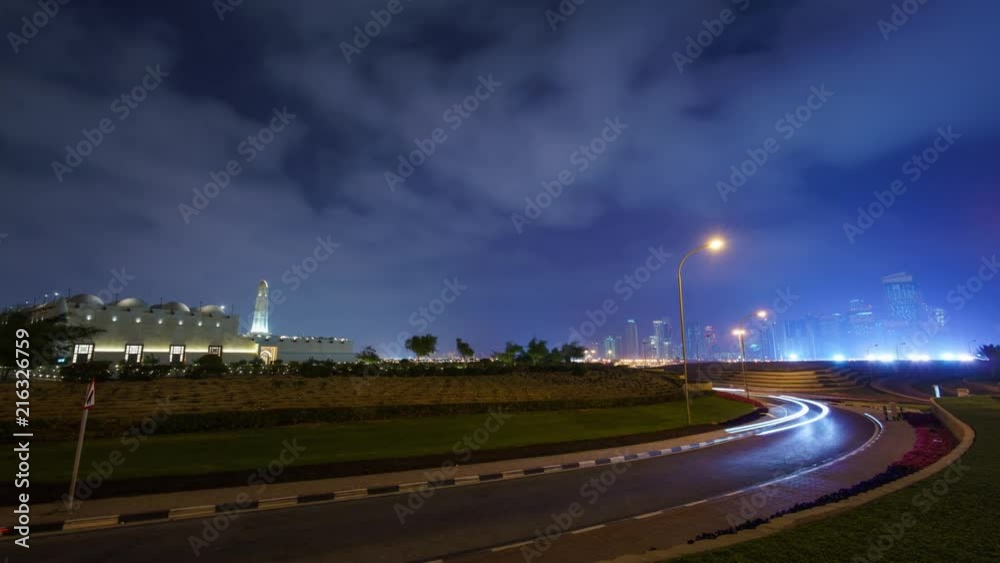 Night view of Qatar State Mosque and West Bay in the background with traffic passing in the foreground. Night view of Qatar State Mosque and West Bay in the background with traffic passing in the foreground.