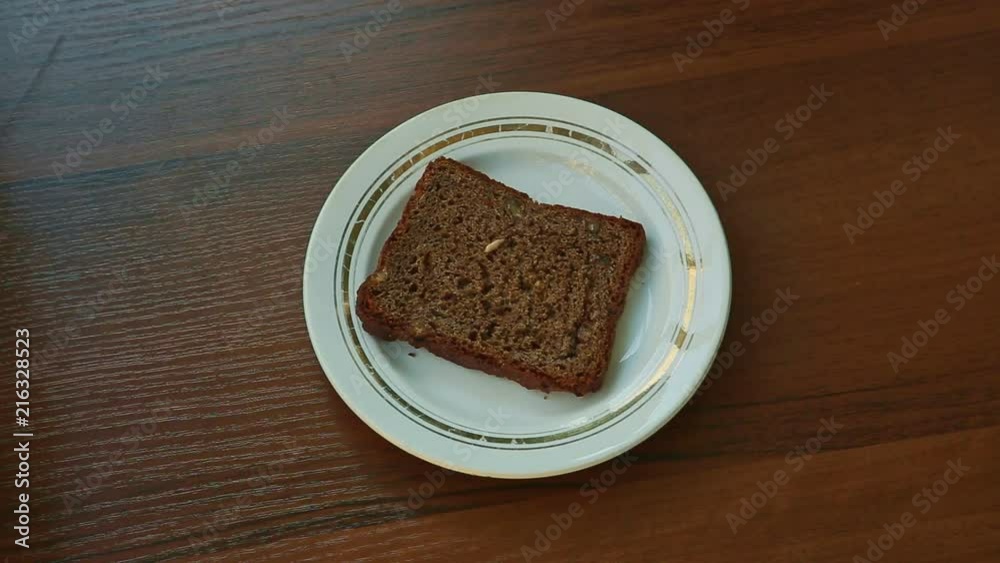 hand puts plate with slice of rye bread with sunflower seeds