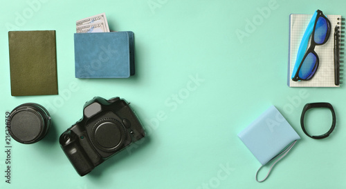 Gadgets and accessories layout on pink pastel background. Photographic equipment, purse with dollars, smart clock, smartphone, notebook, sunglasses, passport, power bank. Concept travel, copy space.