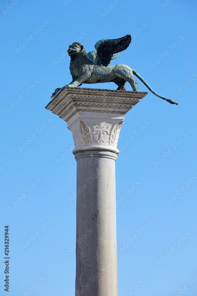 Naklejka premium San Marco winged Lion statue on column, symbol of Venice in a sunny day, blue sky in Italy