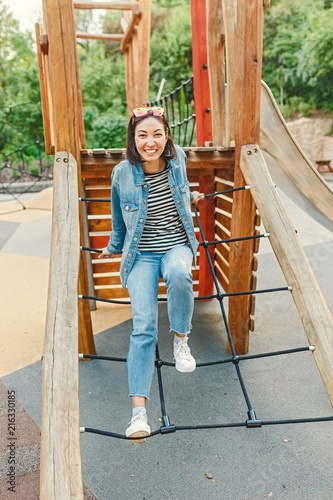 An infantile and happy woman sitting on a kid slide on a playground