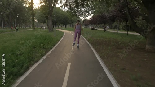 Wallpaper Mural White hansom brown hair girl in tight violet pants woman riding roller skates on bike road in park, during summer golden hour Torontodigital.ca