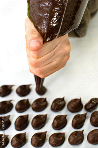 WOMAN HAND PREPARING CHOCOLATE TRUFFLES AGAINTS WHITE BACKGROUND photo