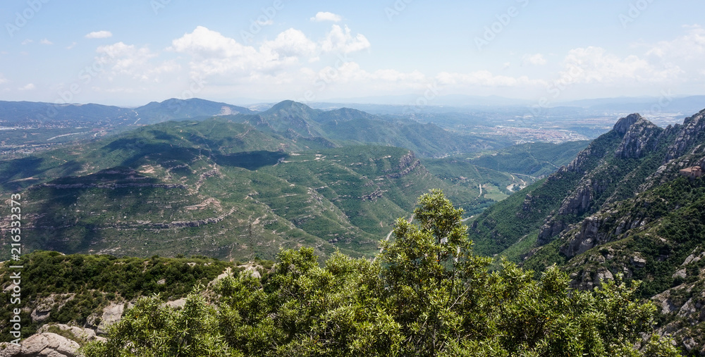 A beautiful view of the multi-peaked mountain range from high above, Montserrat, near Barcelona, Spain. Shadows of the clouds lie on a mountain's peak.