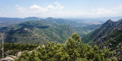 A beautiful view of the multi-peaked mountain range from high above, Montserrat, near Barcelona, Spain. Shadows of the clouds lie on a mountain's peak. © Sa_Shiko