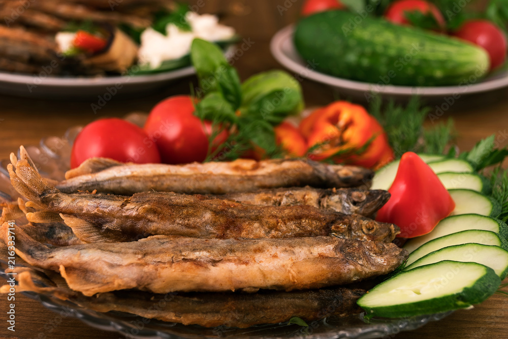 Whole fried fish with garnish of fresh vegetables, basil leaves and dill. Whole fried fish with garnish of fresh vegetables, basil leaves and dill.