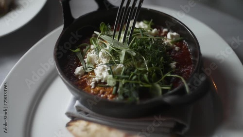 Shakshuka breakfast breaking an egg yolk. photo