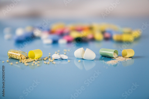 open tablets pills capsules blue background photo