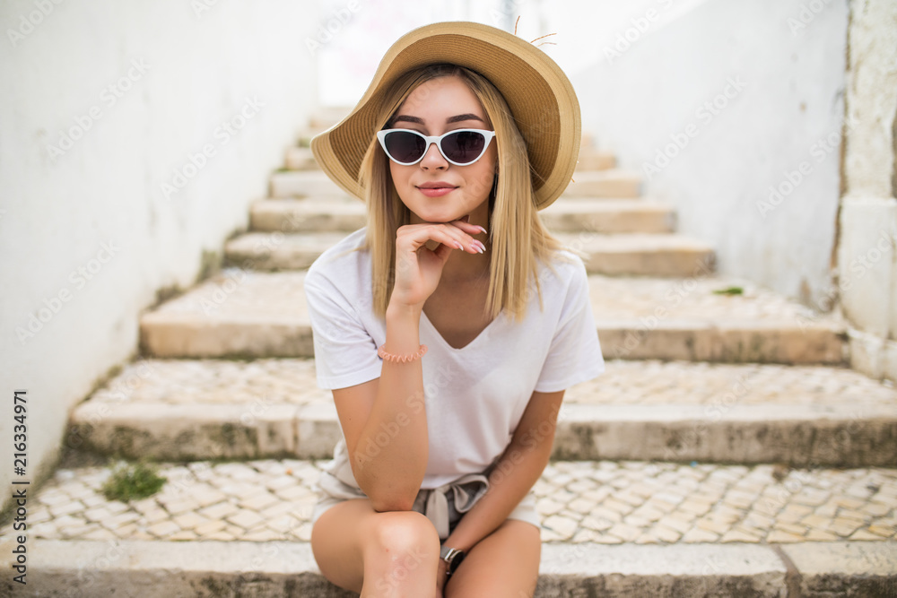 Beautiful young caucasian woman smiling in urban background. Blond girl wearing casual clothes in the street.