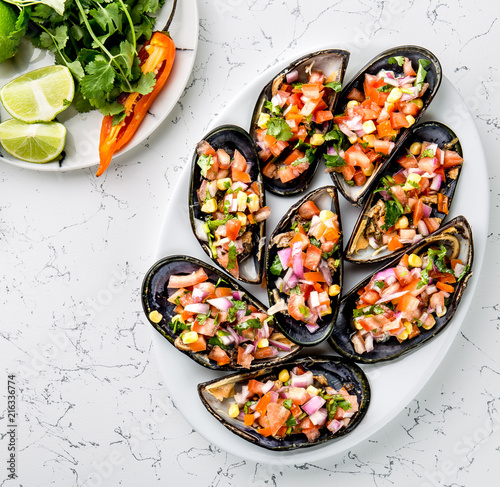 PERUVIAN FOOD. Choros a la chalaca. Big mussels, choros zapatos seasoned with purple onion, tomatoes, corn and lemon. Top view, white background. Traditional peruvian dish