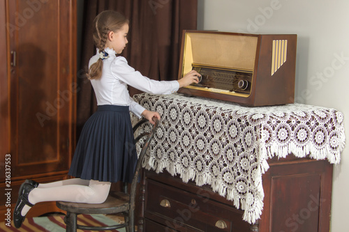 Little girl listens to old radio.