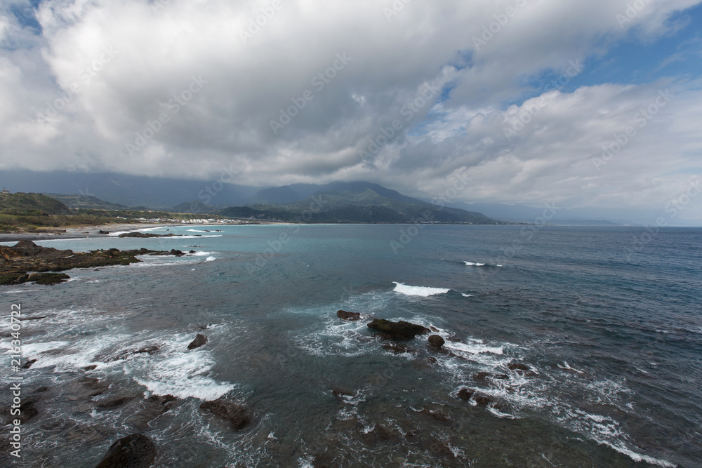 Three Saints Island, Taitung Taiwan, Pacific Coast. Seascape Background Image - Sanxiantai scenic area, blue ocean waves with small rock formations in the foreground.