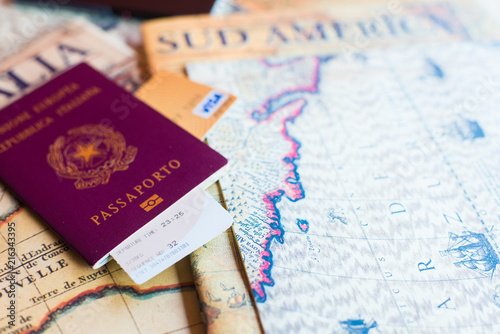 An Italian passport with a smartphone over a tourist magazine of South America, on a light background.