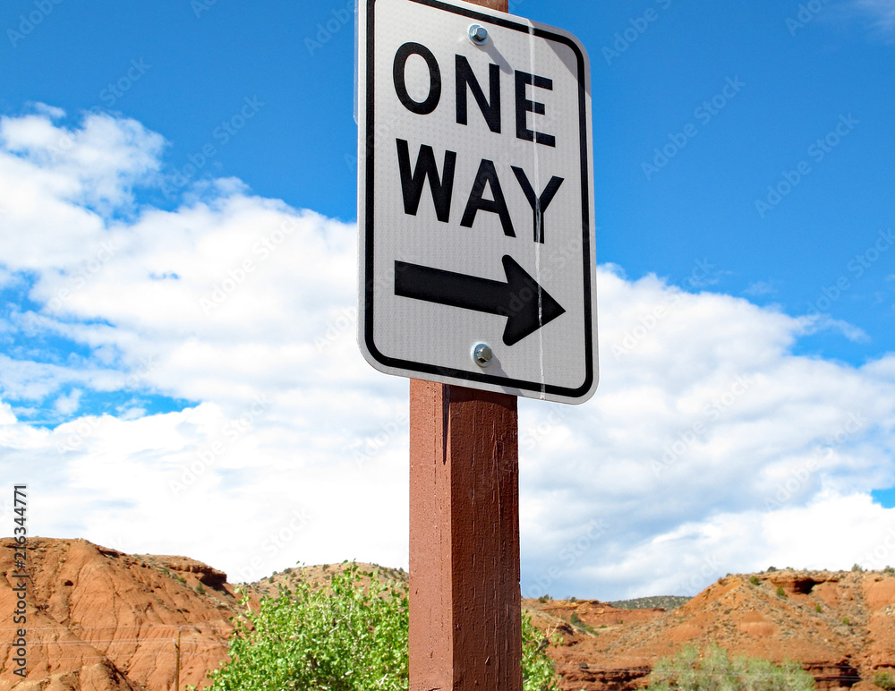 One Way Street Sign On A Small Desert Road With Red Rock And Blue Sky