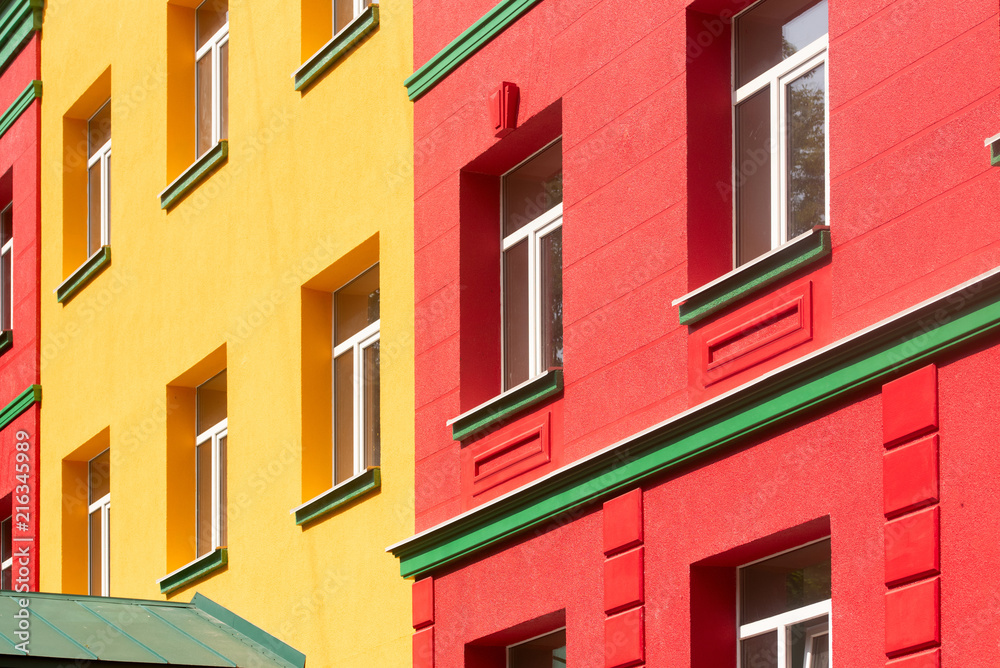 brightly colored building in burgundy and yellow with green cornice, building element